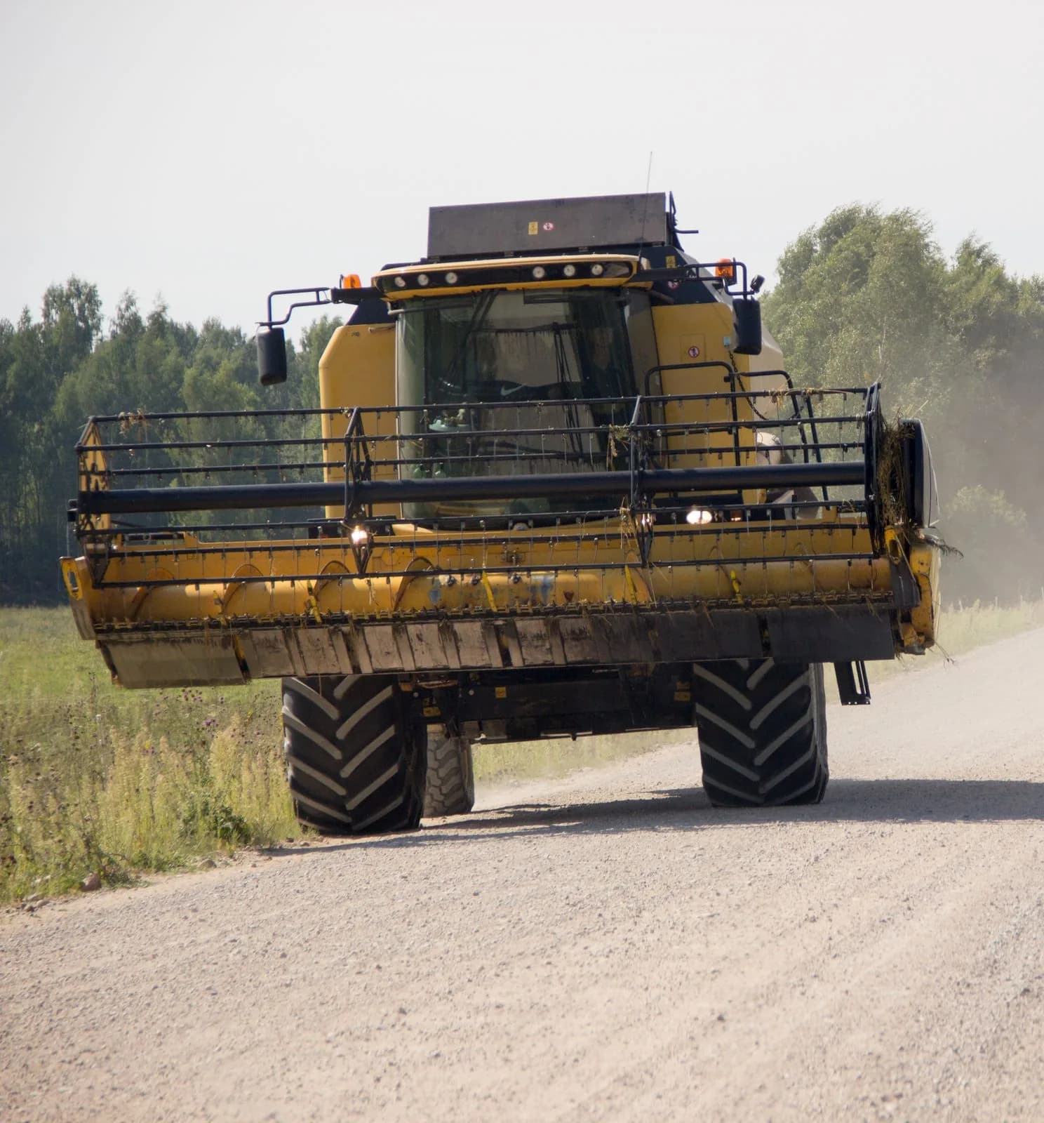 Combine harvester travelling along a rural dirt road