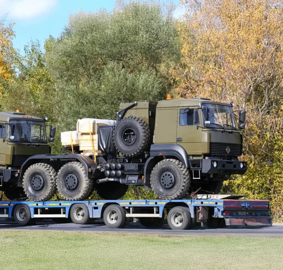 Military trucks loaded on a low-bed semi-trailer